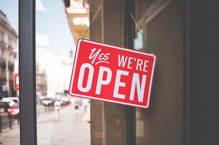 Red 'Yes, We're Open' sign displayed on a storefront window, symbolizing business readiness and community support.