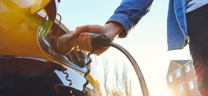 Person plugging an electric vehicle into a home charger, illustrating EV charging options for Pacific Palisades homeowners