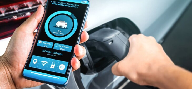 Driver checks EV charging status on a smartphone while connecting the charging cable.