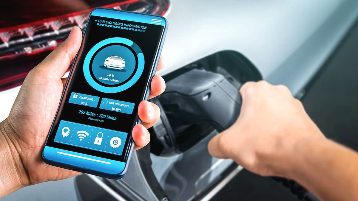 best-outdoor-ev-charger-features-pacific-palisades-og1 Driver checks EV charging status on a smartphone while connecting the charging cable.